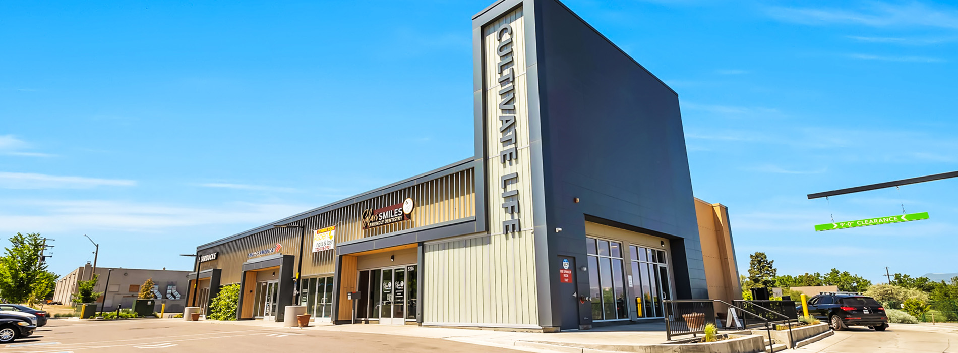 The image shows a modern building with a prominent architectural feature, situated in an outdoor setting under clear skies.