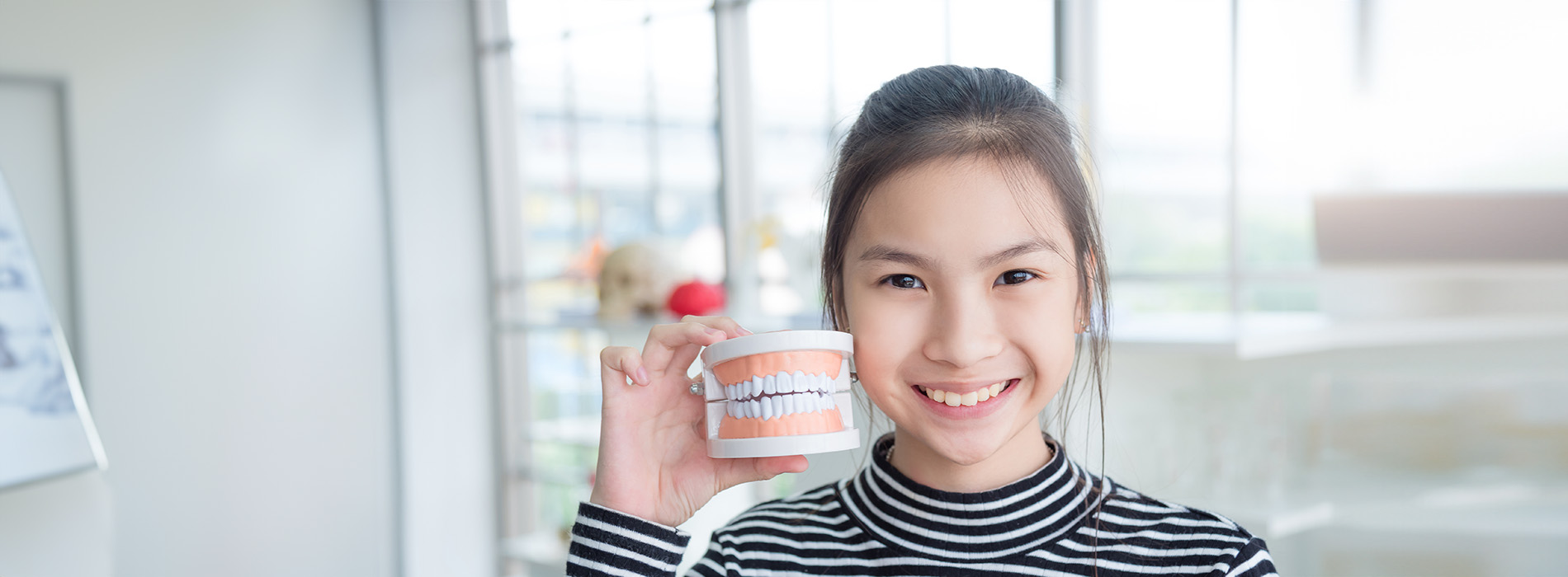 A young woman holding a cup of coffee, smiling at the camera.