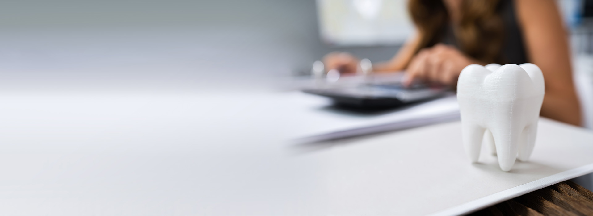 The image features a person sitting at a desk, working on a computer with a document in front of them. On the desk, there is also a toothbrush holder containing a toothbrush.