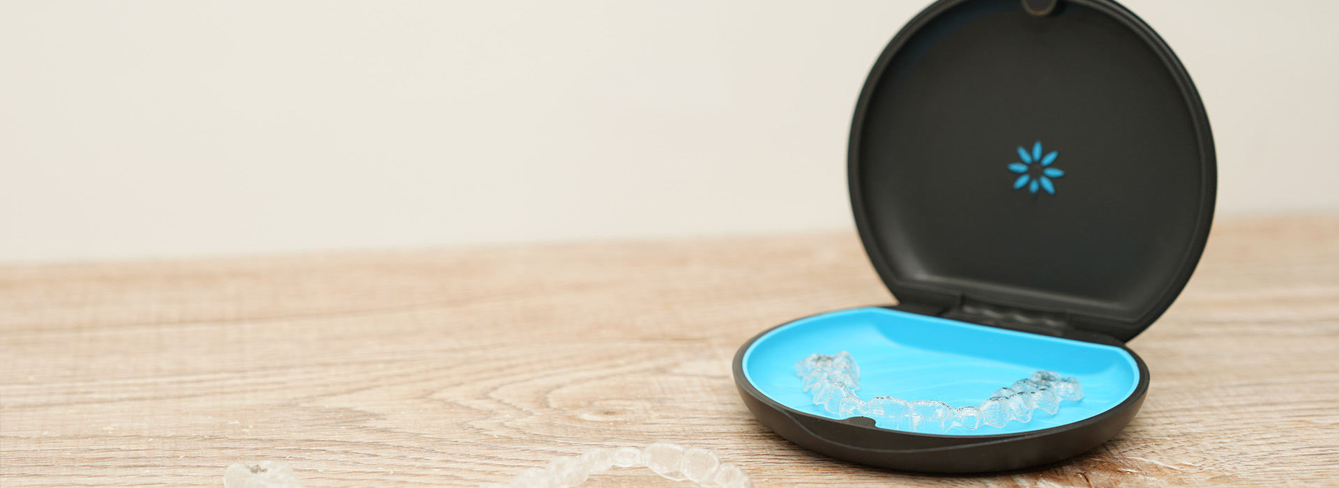 A black smartphone charging dock with a blue circular base, placed on a wooden surface.