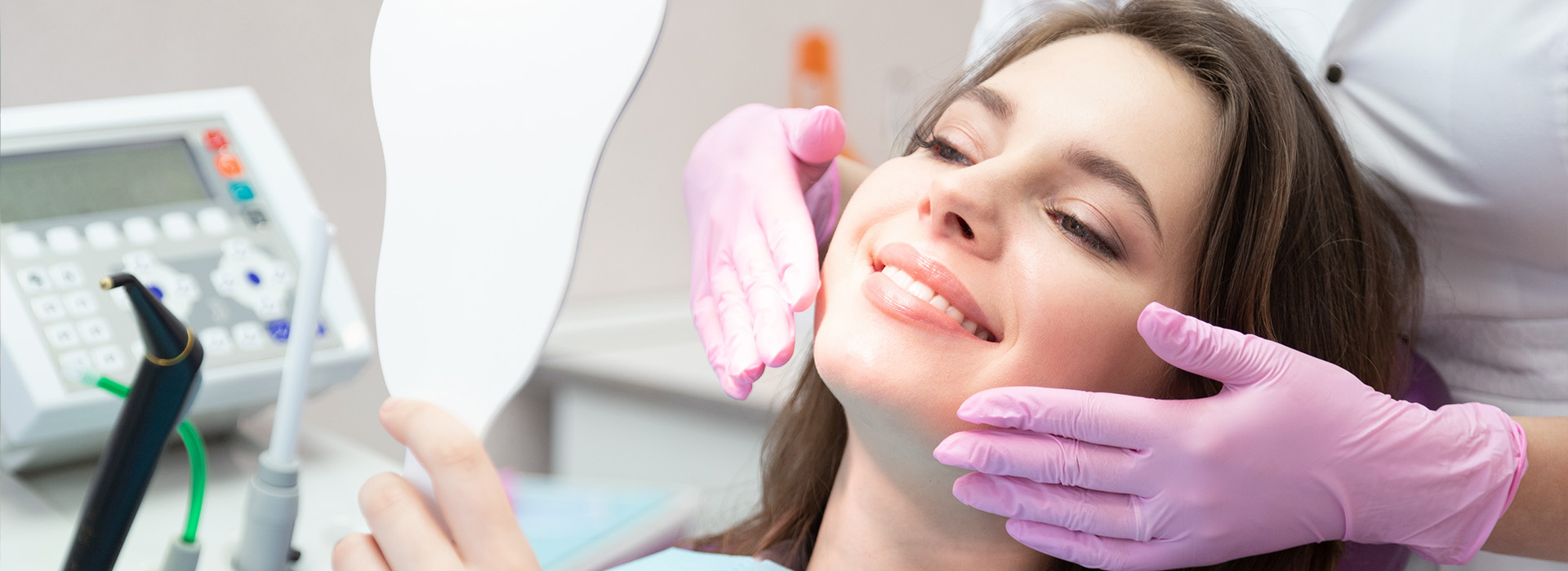 The image shows a woman in a dental chair receiving dental care, with a dental professional performing an examination using a mirror.