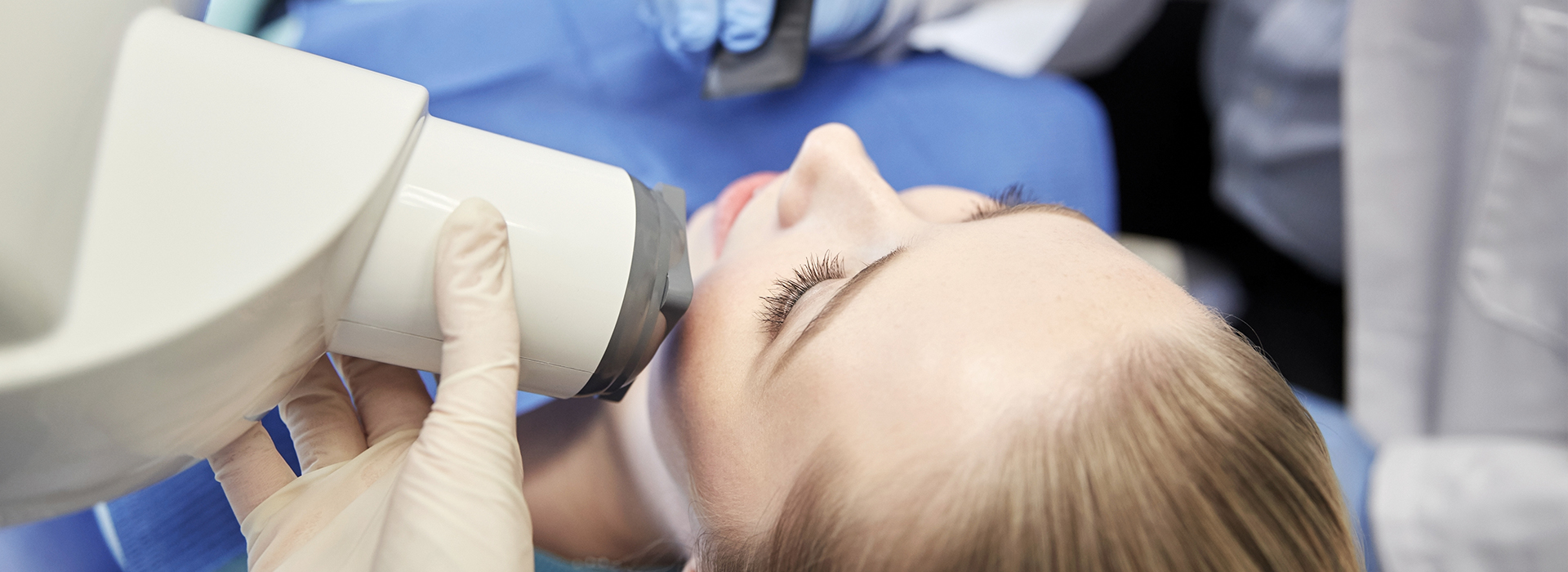 A person receiving a dental implant procedure, with a dentist using a magnifying loupe to examine the patient s teeth.