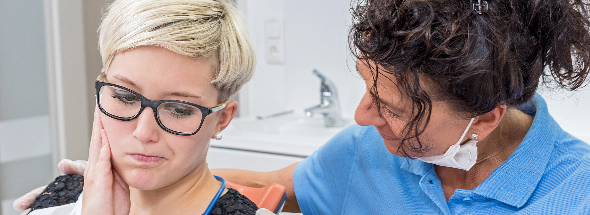 A woman sitting in a dental chair, receiving care from a dentist.