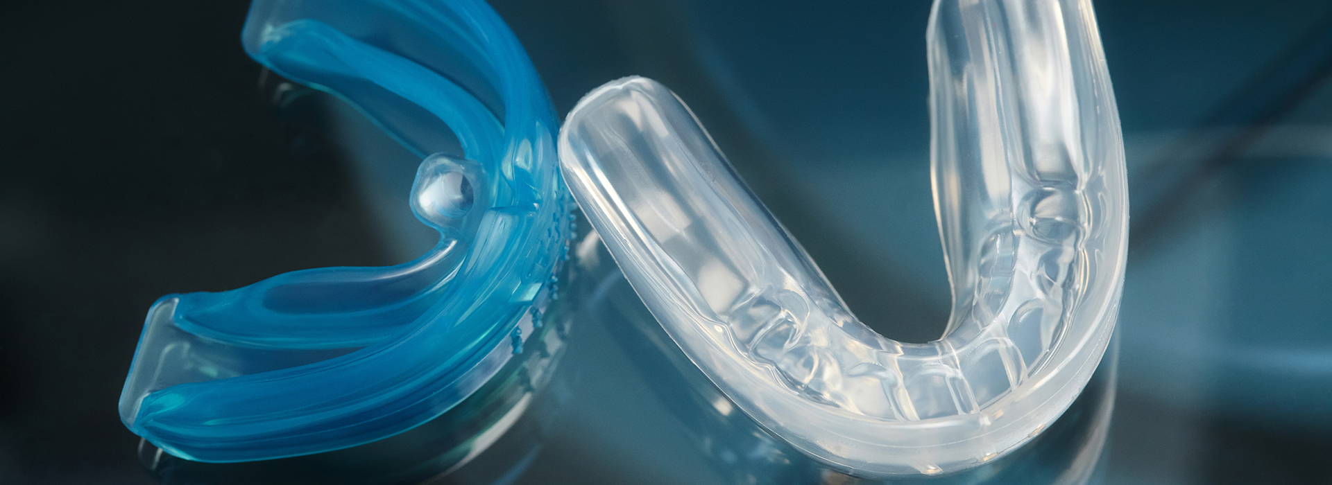 Clear plastic toothbrush head with blue bristles against a dark background.