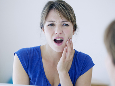 A woman with her mouth open, making a face that suggests she is in pain or experiencing discomfort.