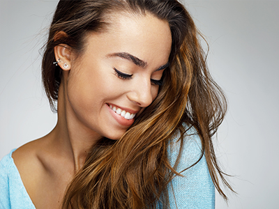 A young woman with long hair and a bright smile, looking to the side.