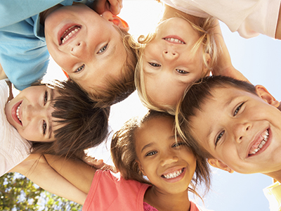 The image shows a group of children posing for the camera with smiles on their faces.