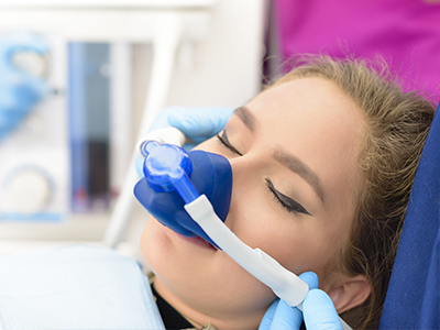 Woman receiving oxygen therapy with a medical mask and hose attached to her face.